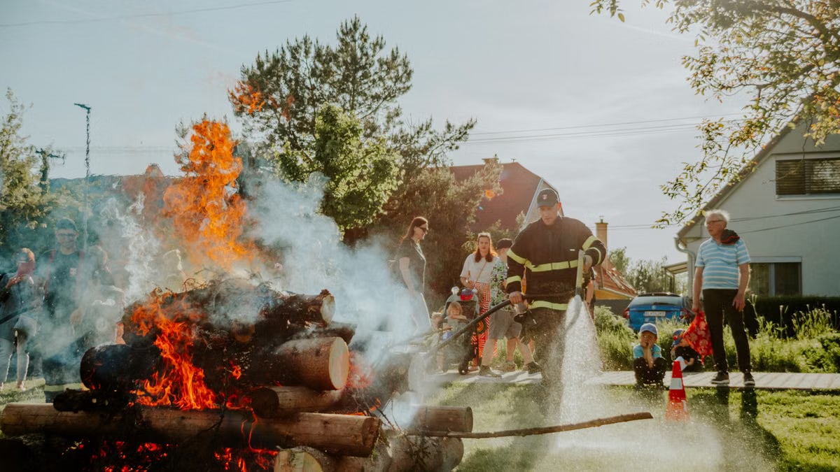 Firefighter putting out a controlled fire during a training demonstration in a residential area.